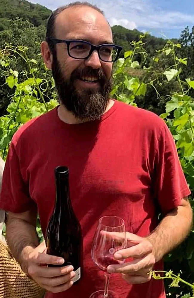 Oriol Artigas a la vinya amb una ampolla i una copa de vi